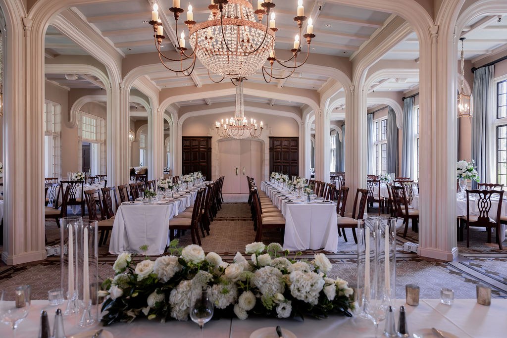 Elegant hall with chandeliers, long tables and white florals