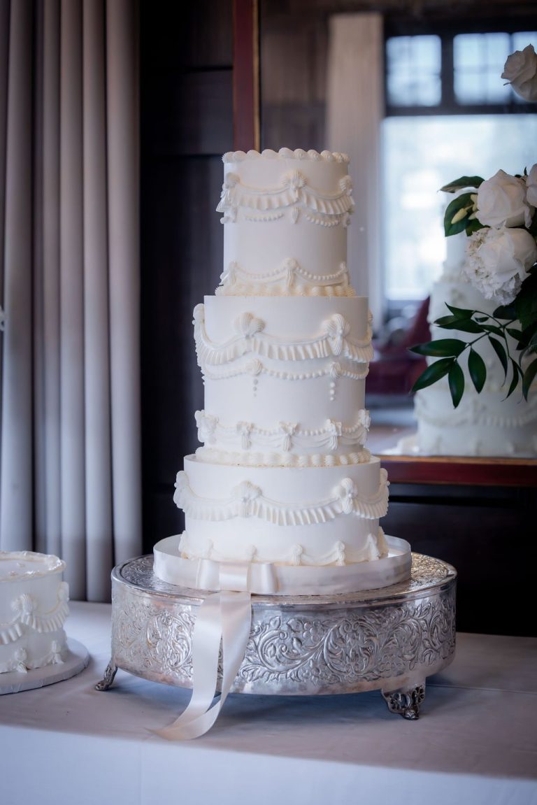 Tall white tiered wedding cake on silver stand