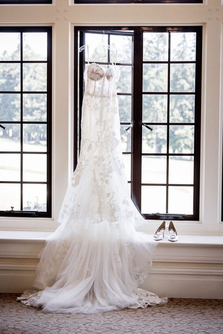 Lace gown hanging in window with shoes below
