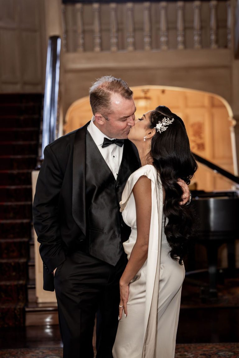 Groom kissing bride forehead near grand piano
