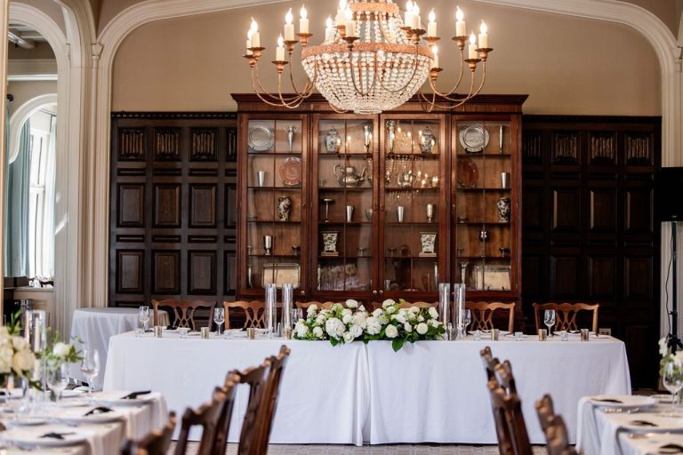 Head table with white florals under crystal chandelier