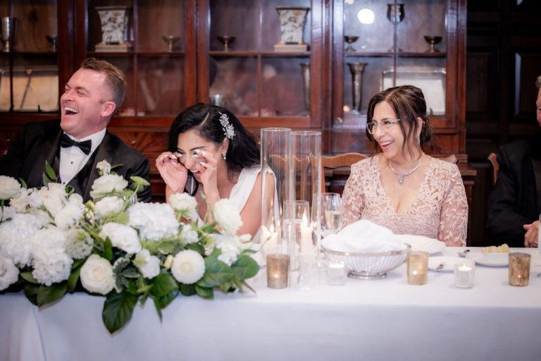 Bride wipes happy tears beside laughing groom