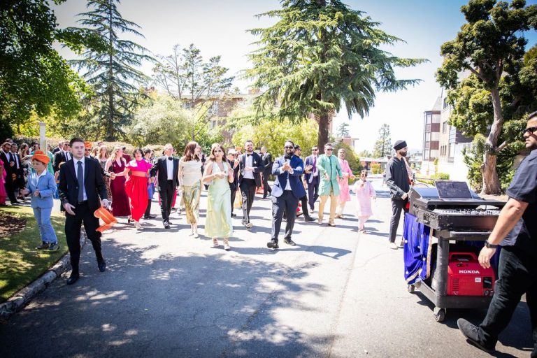 Wedding party processes down path with cheering guests