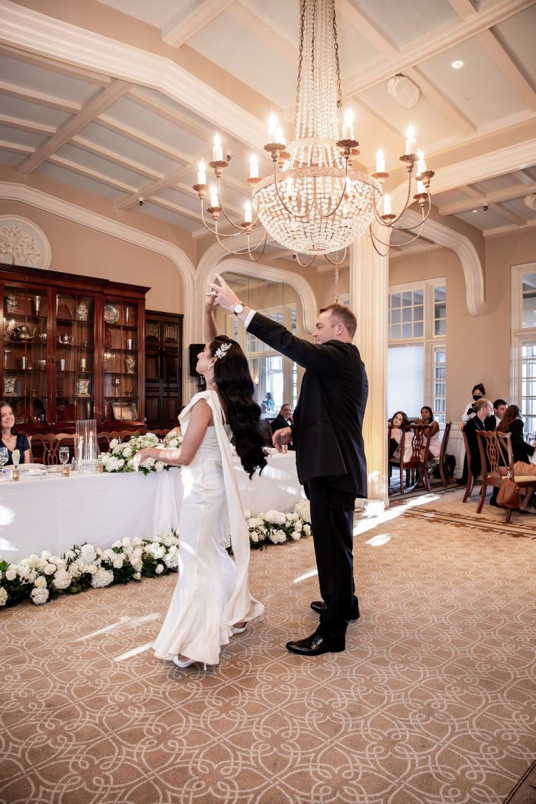 Groom twirling bride during first dance by head table