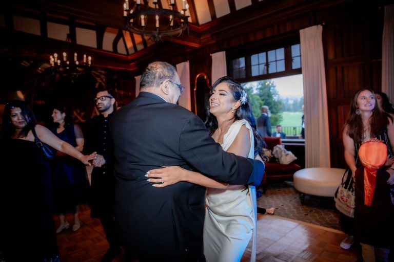Bride slow dancing with father figure at reception