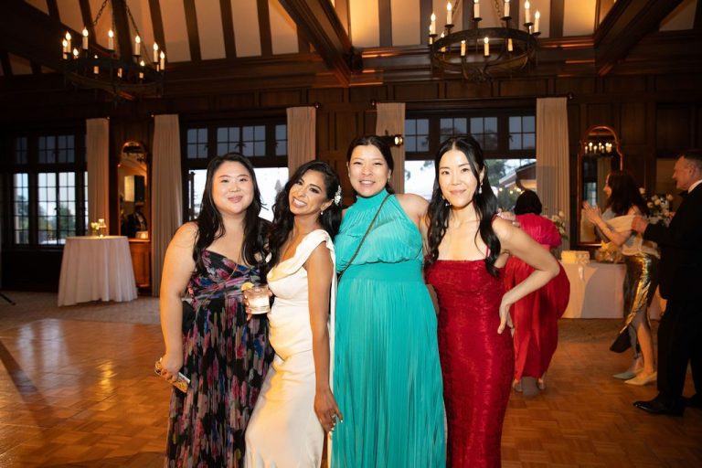 Four women in gowns posing together at reception
