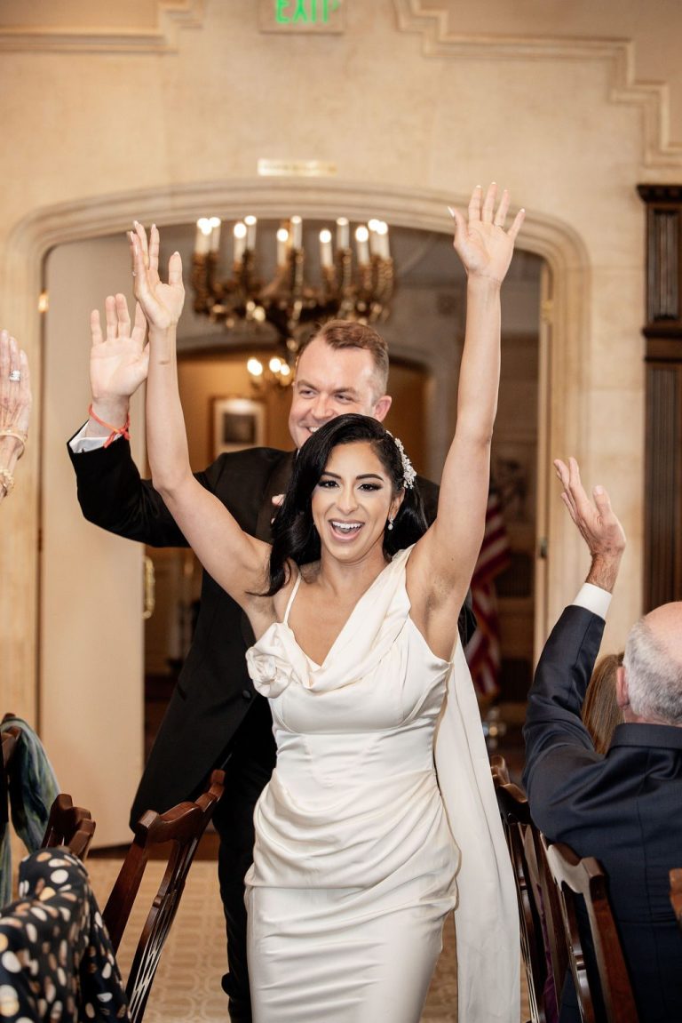 Bride and groom cheering with arms raised, joyful entrance