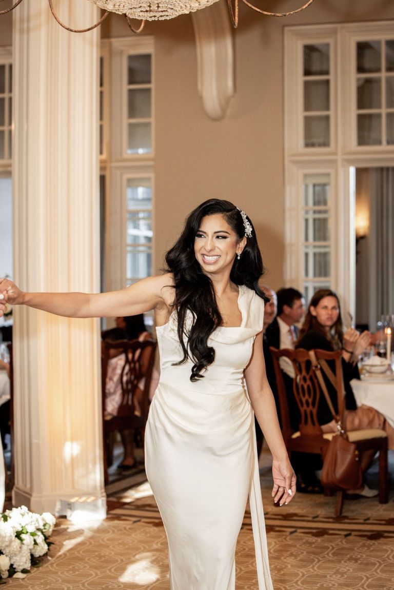 Bride posing gracefully with arm extended on dance floor