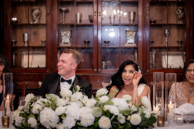 Groom and bride smiling at candlelit head table