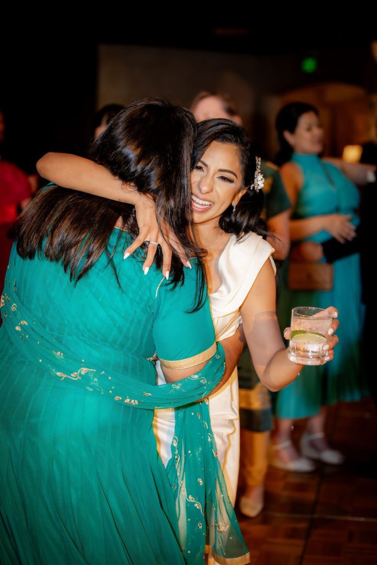 Bride hugging guest in teal sari warmly