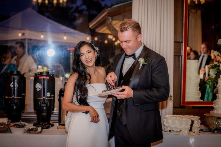 Bride and groom smiling with cake plate at reception