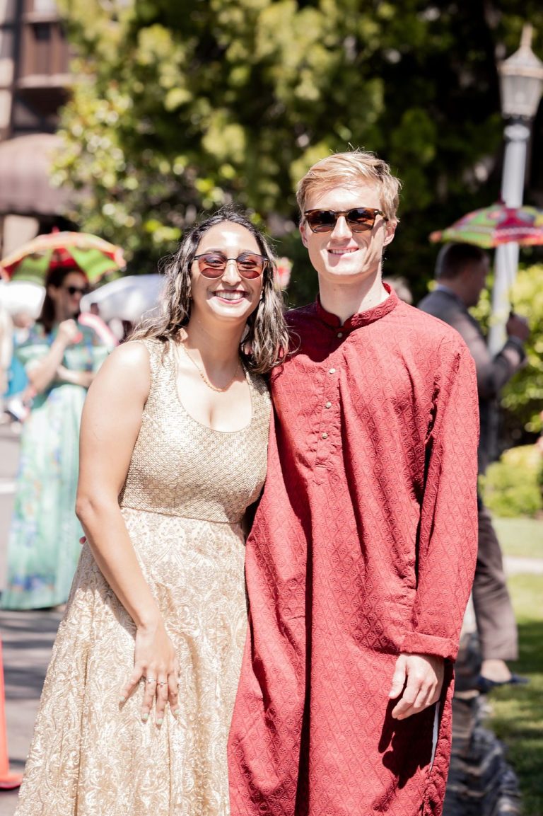 Smiling couple posing in gold dress and red kurta