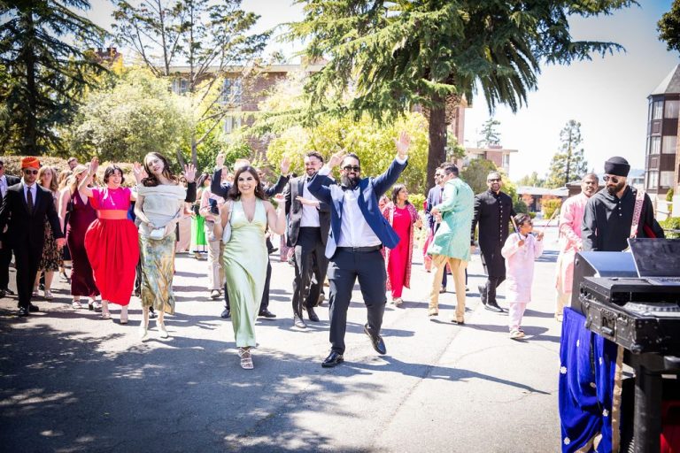Bridal party walks arms raised through cheering crowd
