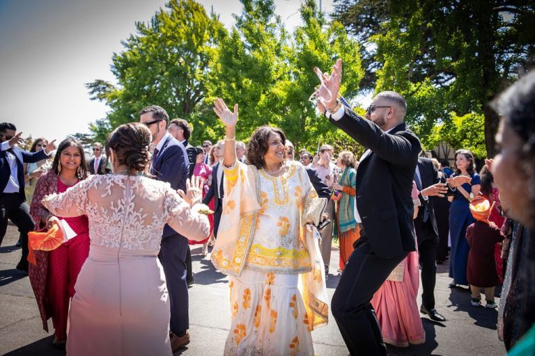 Woman leads dancing crowd with raised arms outdoors