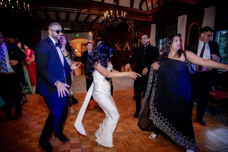Bride dancing with guests under monogram backdrop