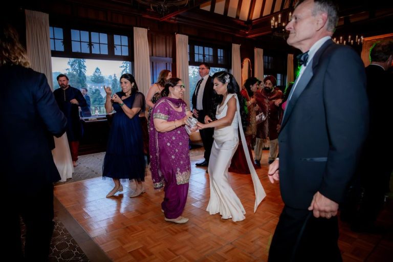 Bride dancing with guests in warm lit hall