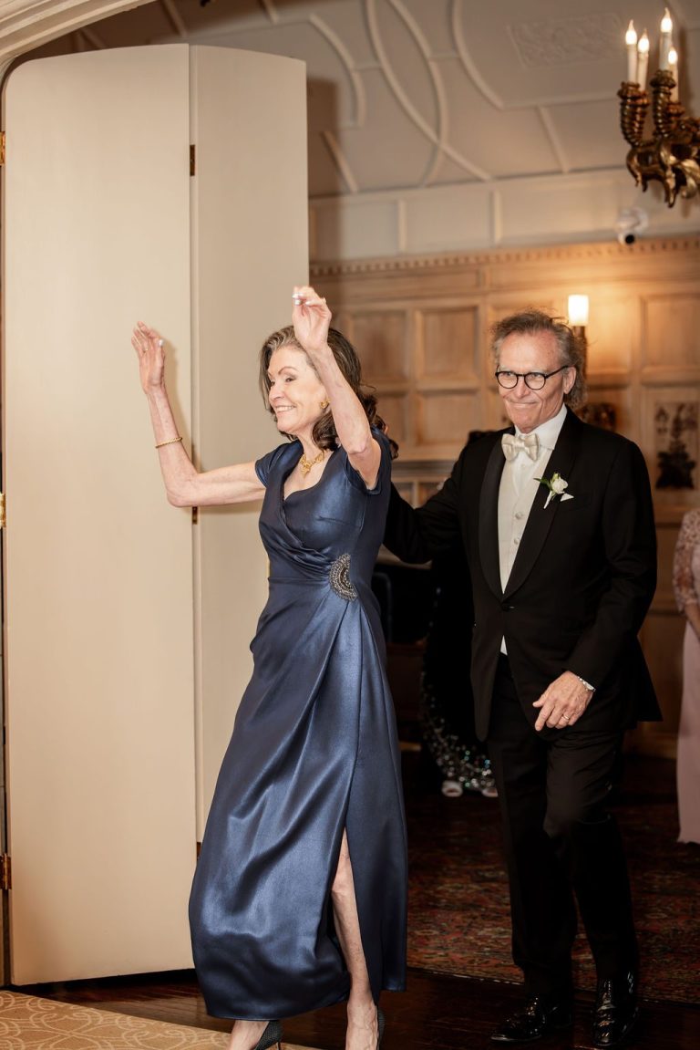 Couple entering reception with arms raised