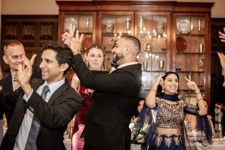 Groom dancing with guests in colorful attire clapping