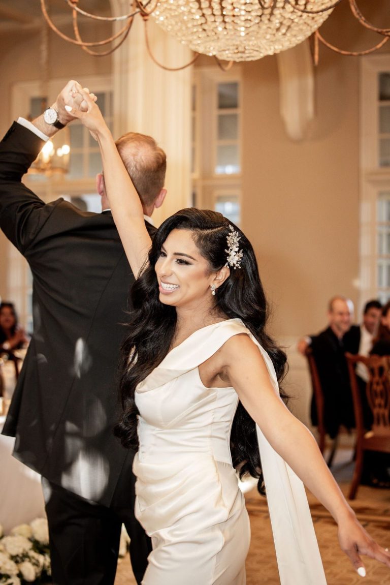 Groom spinning bride during first dance, dress flowing