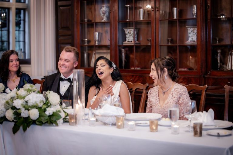 Bride laughing with guests at candlelit head table