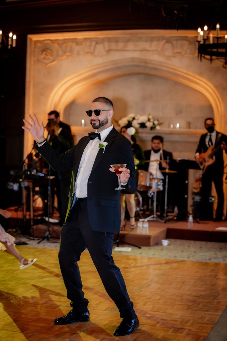 Groom dancing energetically holding a drink