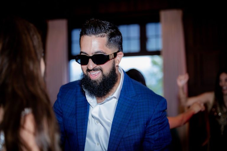 Bearded groom in sunglasses smiling on dance floor