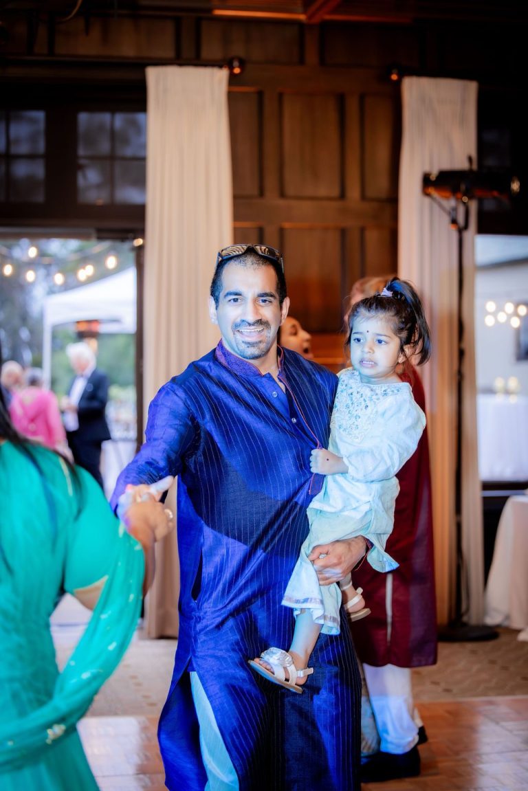 Man in blue attire carrying child on dance floor