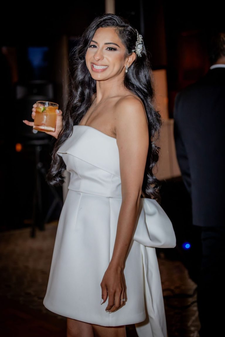 Bride in short white dress holding drink smiling