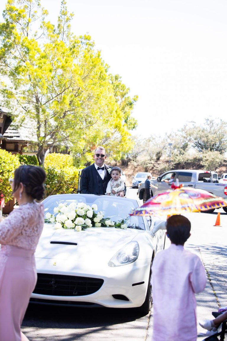 Floral decorated white car with guests nearby