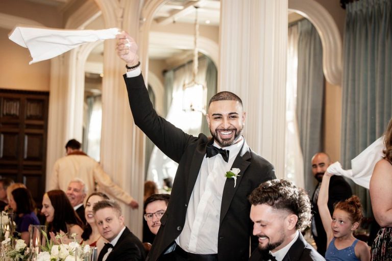 Groom waving white napkin overhead among cheering guests