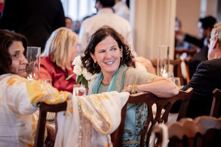 Woman smiling warmly leaning on chair at table