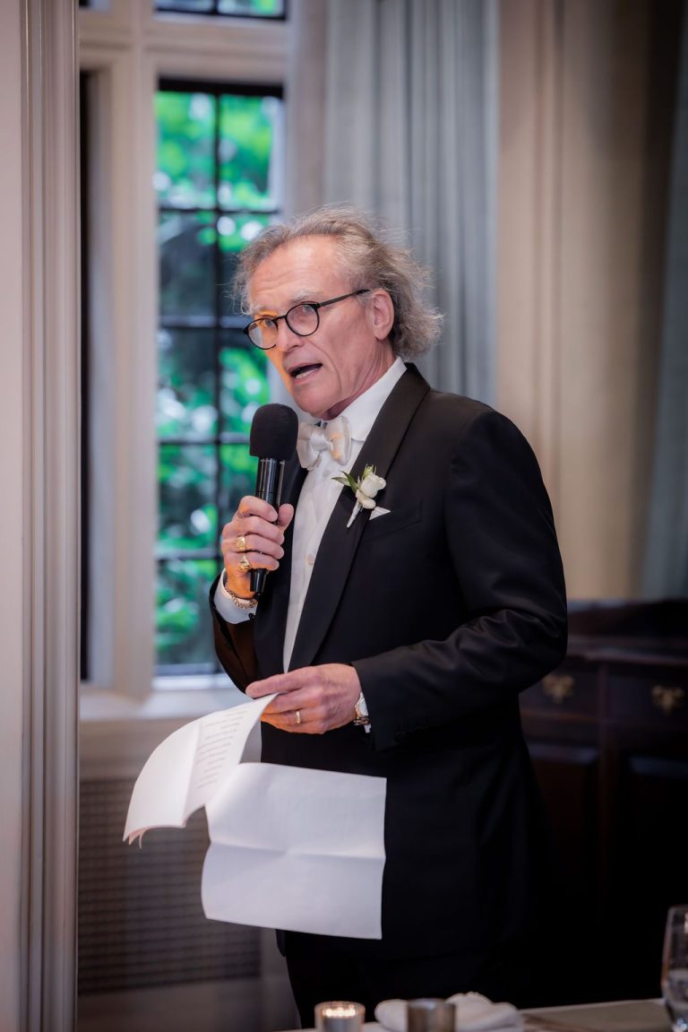 Man reading speech from paper into microphone