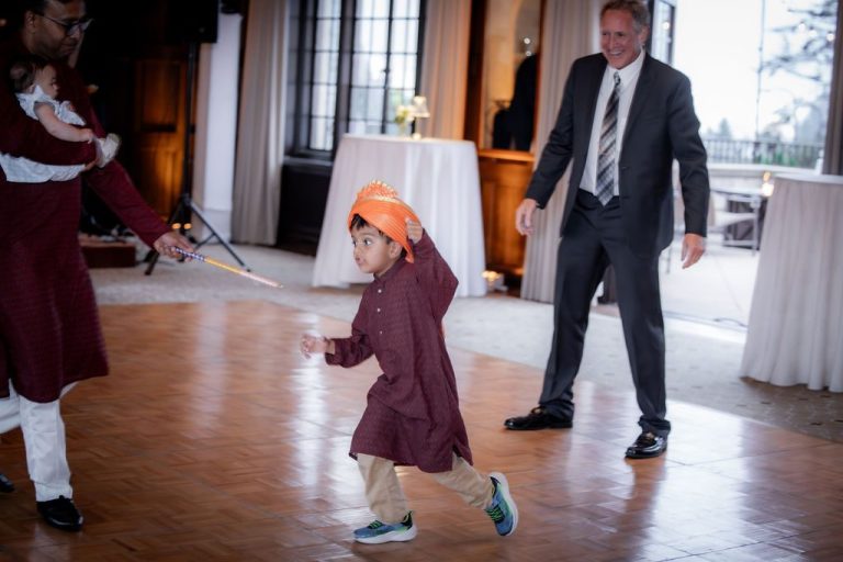 Child in orange headwrap dancing with adults