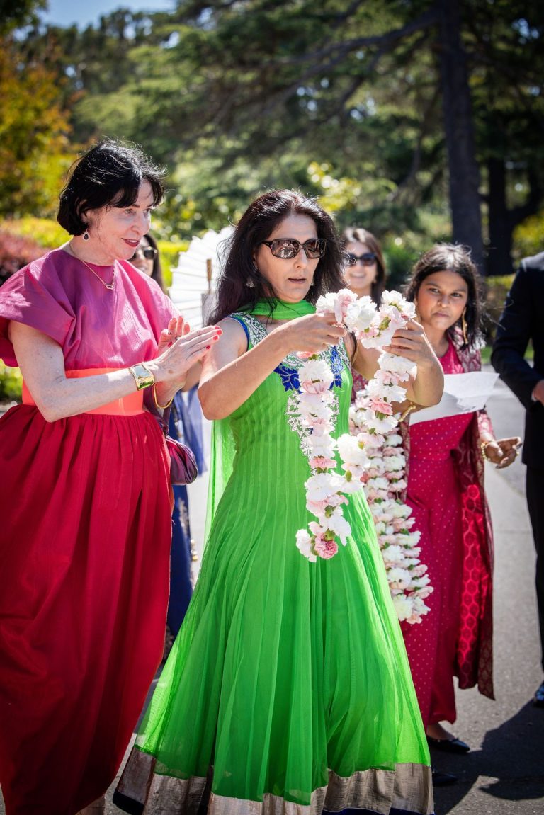Woman in green outfit holding floral garland among guests