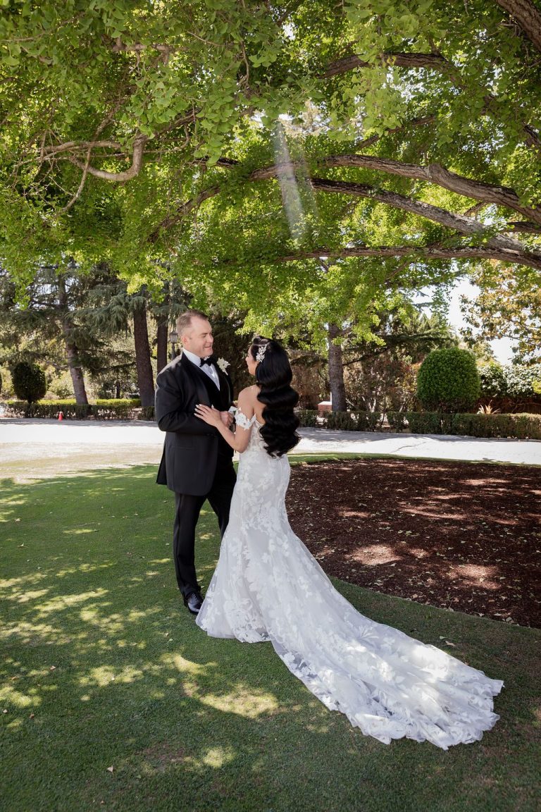 Bride and groom close under shady tree canopy