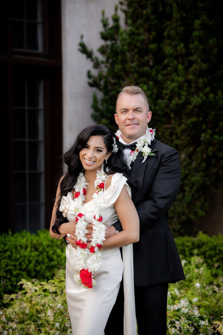 Couple embracing in garden with red floral garland
