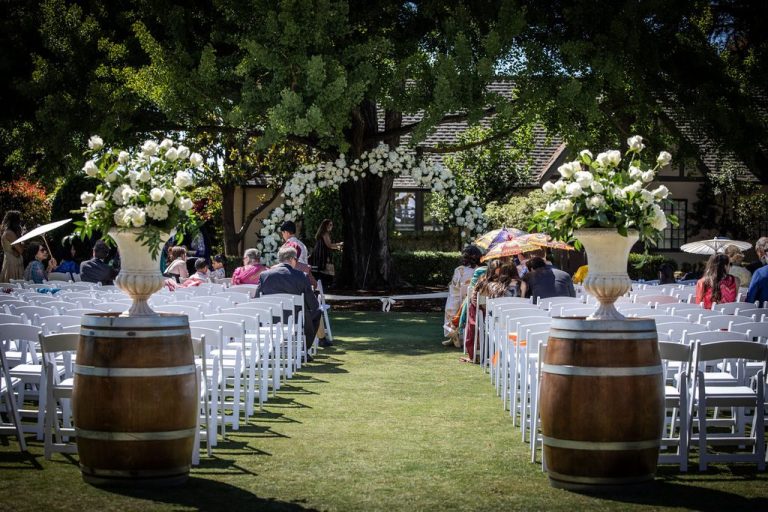 Outdoor ceremony aisle with floral urns on barrels