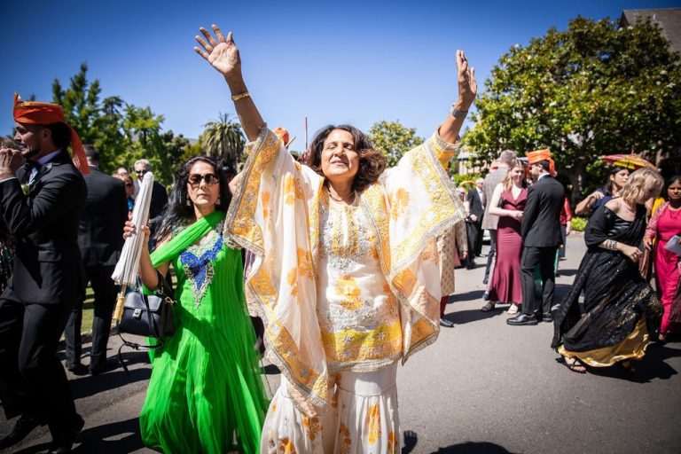Woman in gold dances arms raised amid cheering crowd