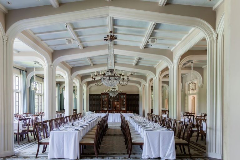 Empty banquet hall set with long tables and chandelier