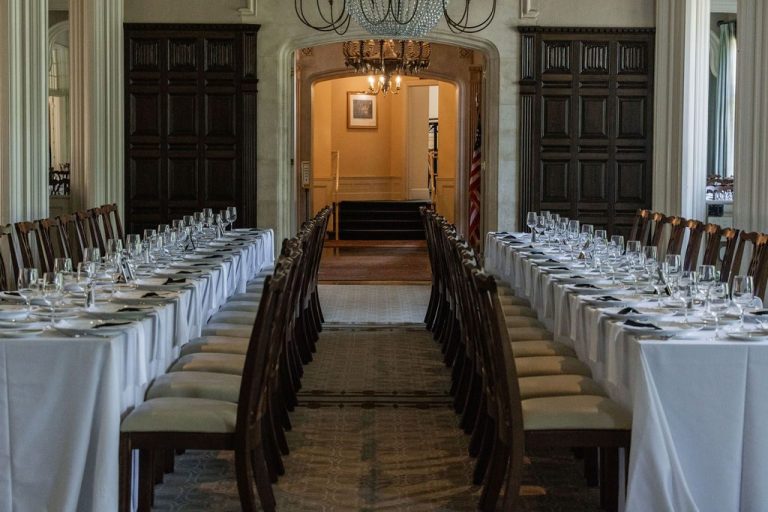 Symmetrical banquet tables framing paneled hallway archway