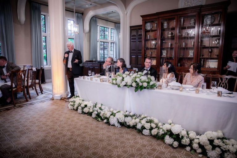 Head table with white florals during a toast