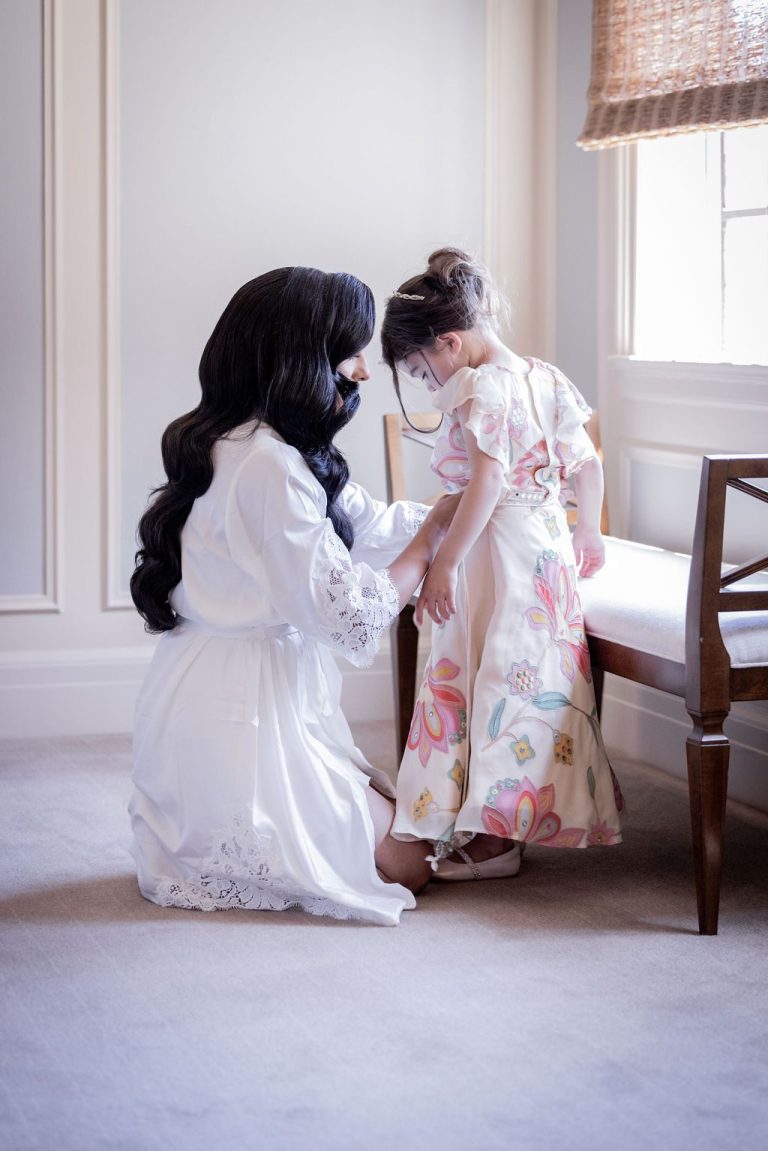 Bride kneeling helping little girl with dress