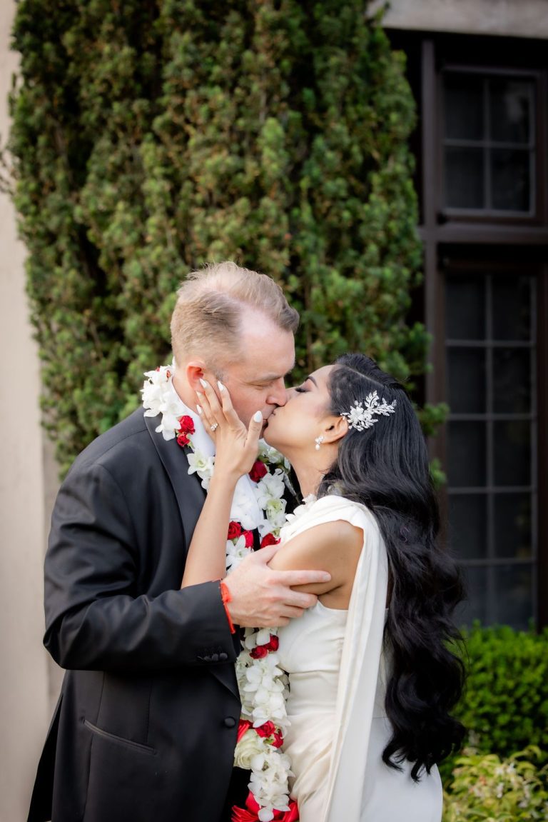 Bride and groom kissing tenderly in garden