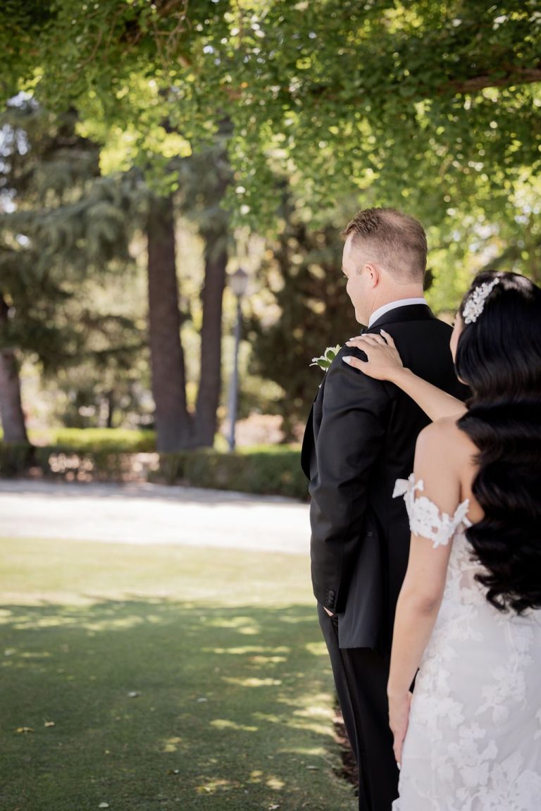 Bride reaching to groom during first look outdoors