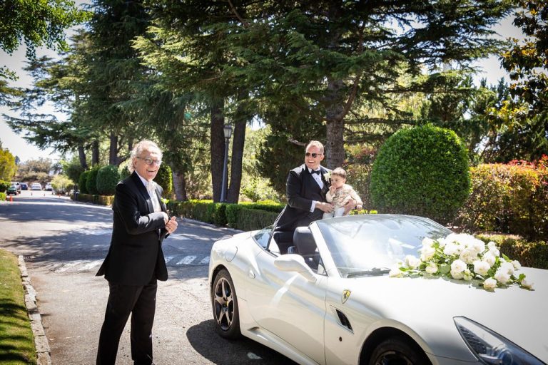 Groom rides standing in decorated white convertible