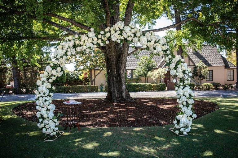 White floral arch under tree, near duplicate frame