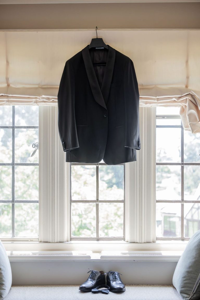 Tuxedo jacket hanging in window with shoes below