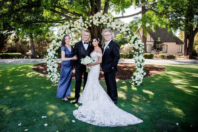 Couple with two guests grouped at floral arch