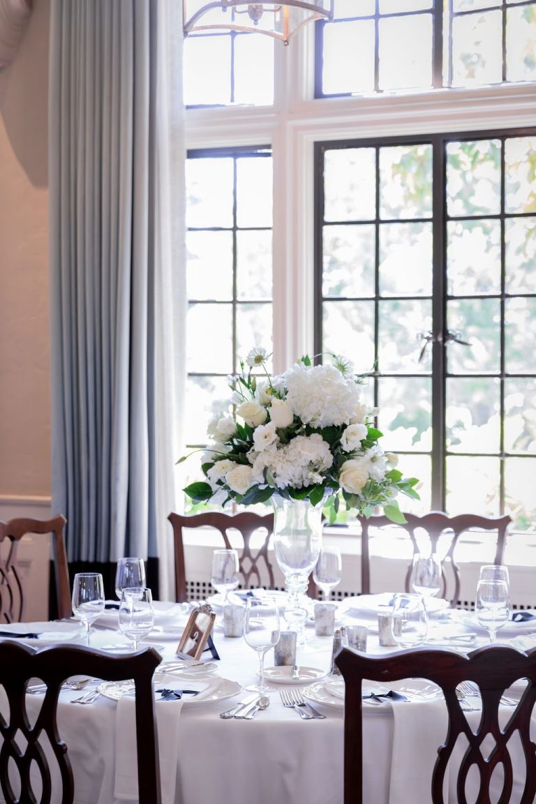 Tall white floral centerpiece on set dining table