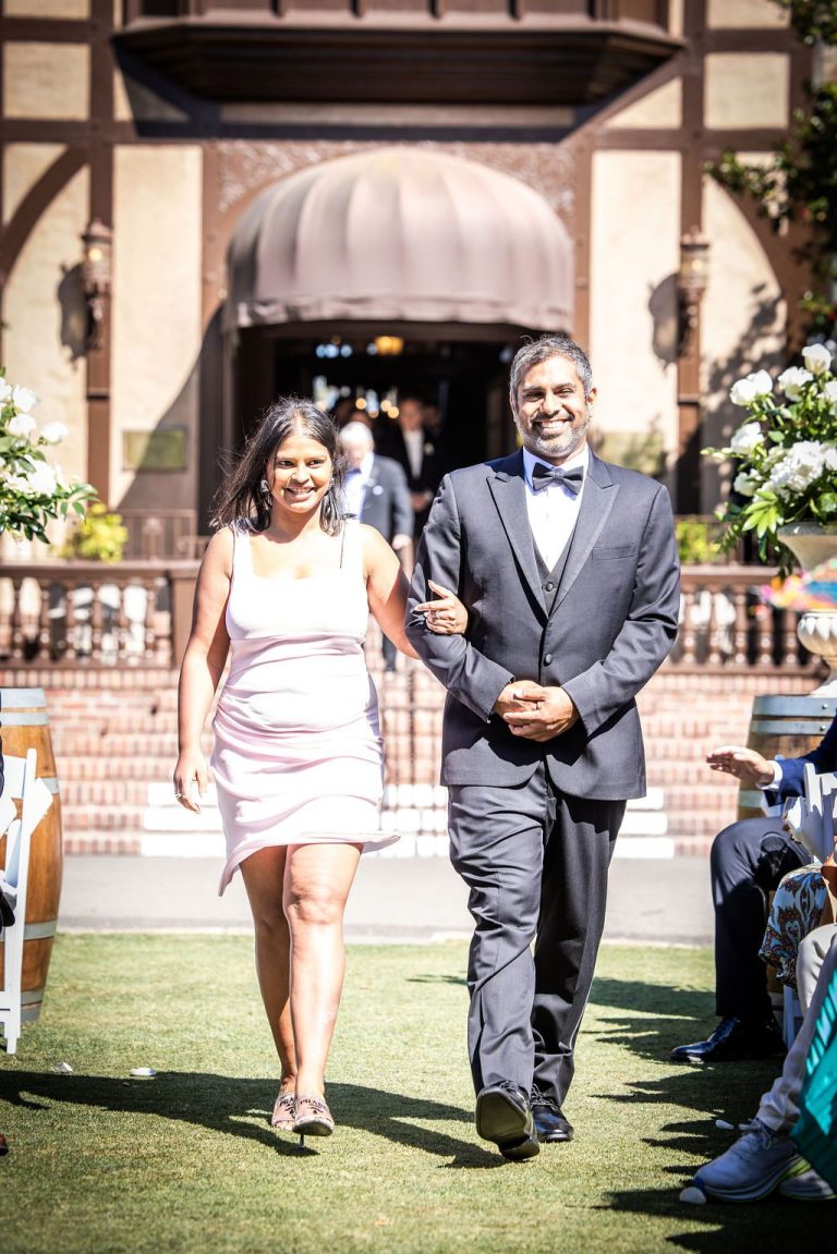 Couple walking aisle past seated guests outdoors
